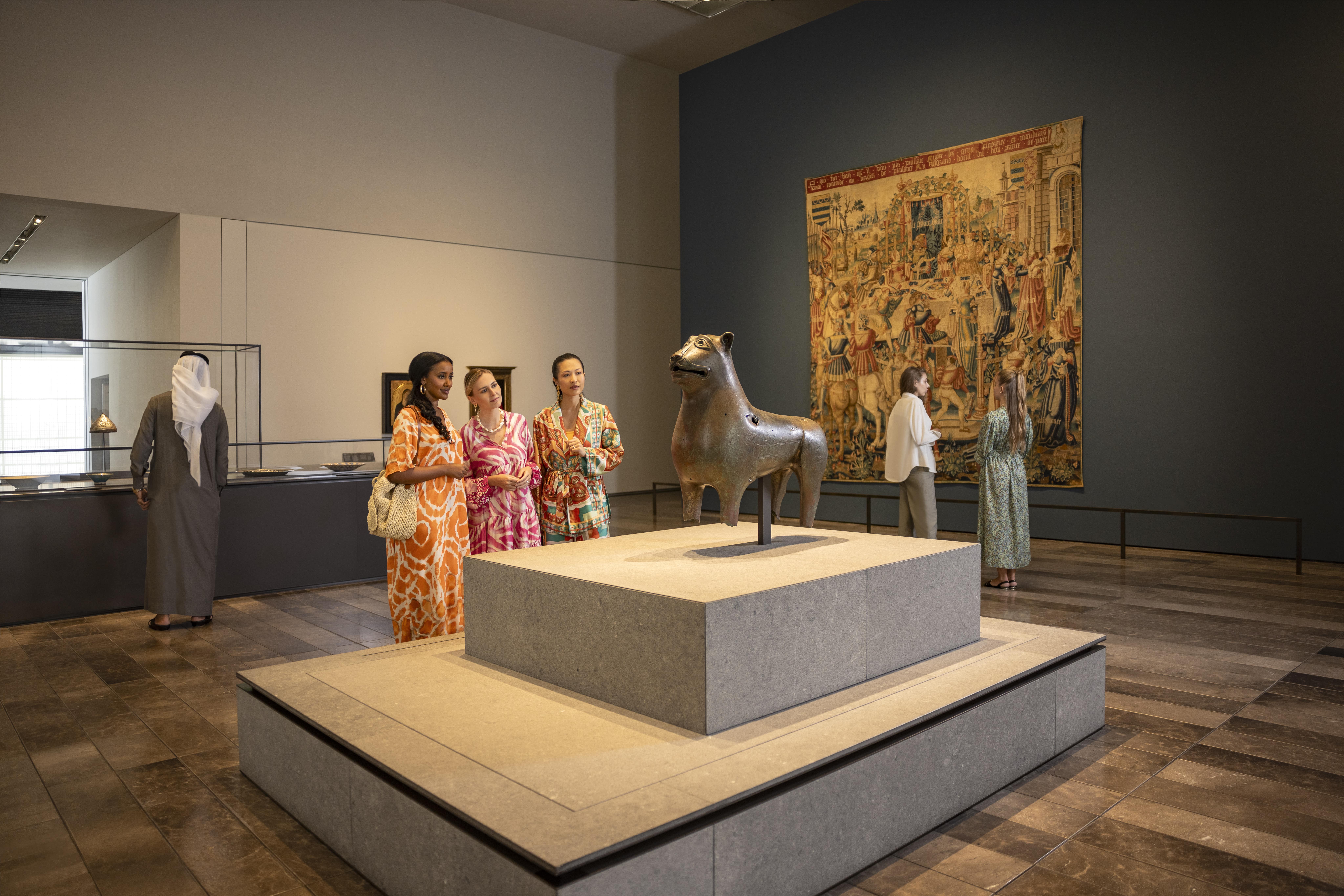 Group admiring historical artifacts and art displays at Louvre Abu Dhabi.