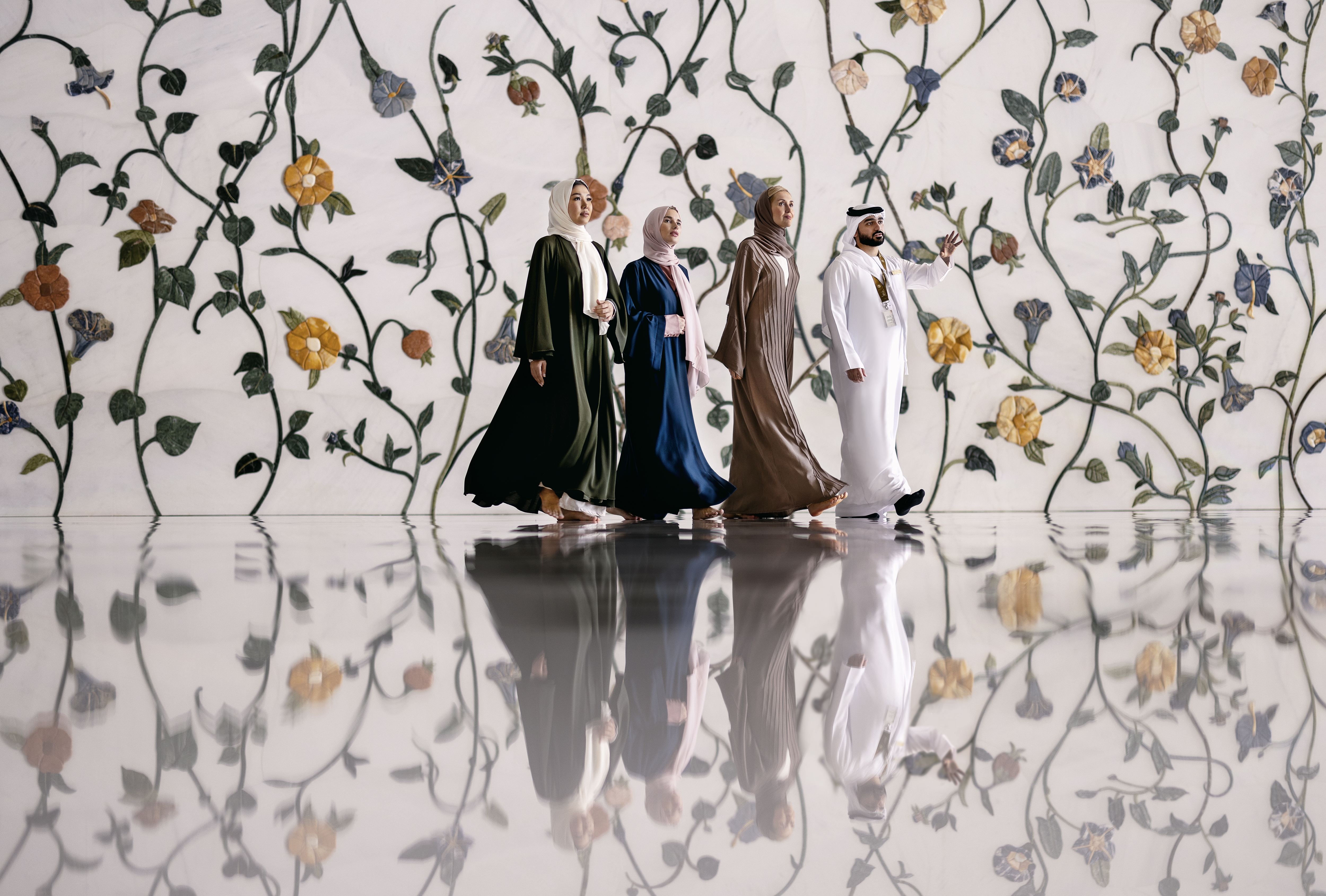 Three women walking with a local guide inside the beautiful Sheikh Zayed Grand Mosque interior